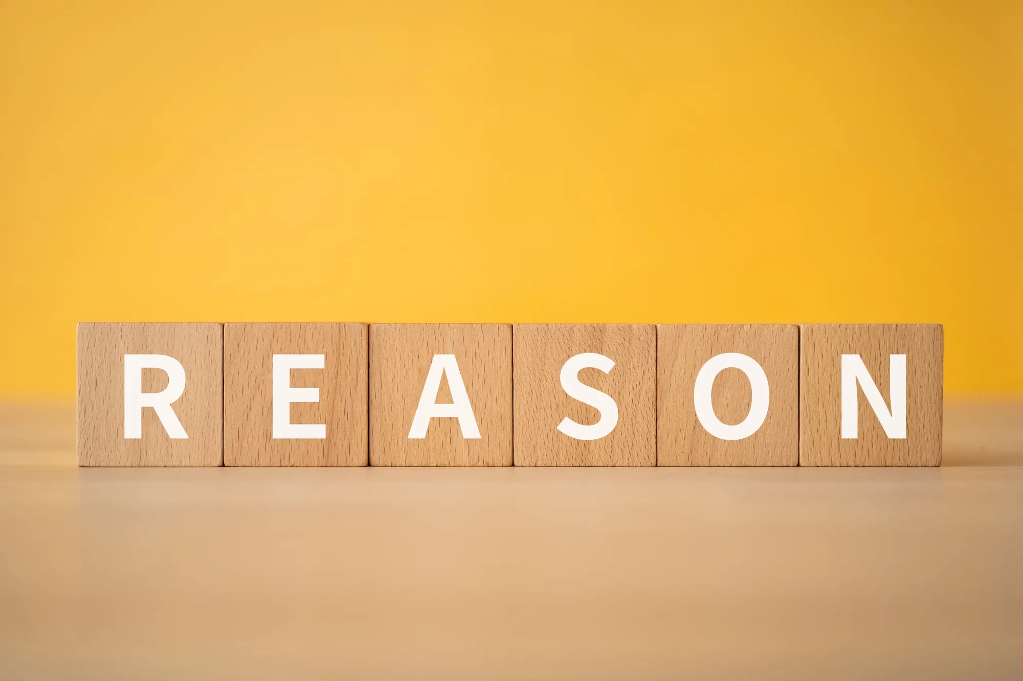 原因・理由のイメージ｜「REASON」と書かれた積み木