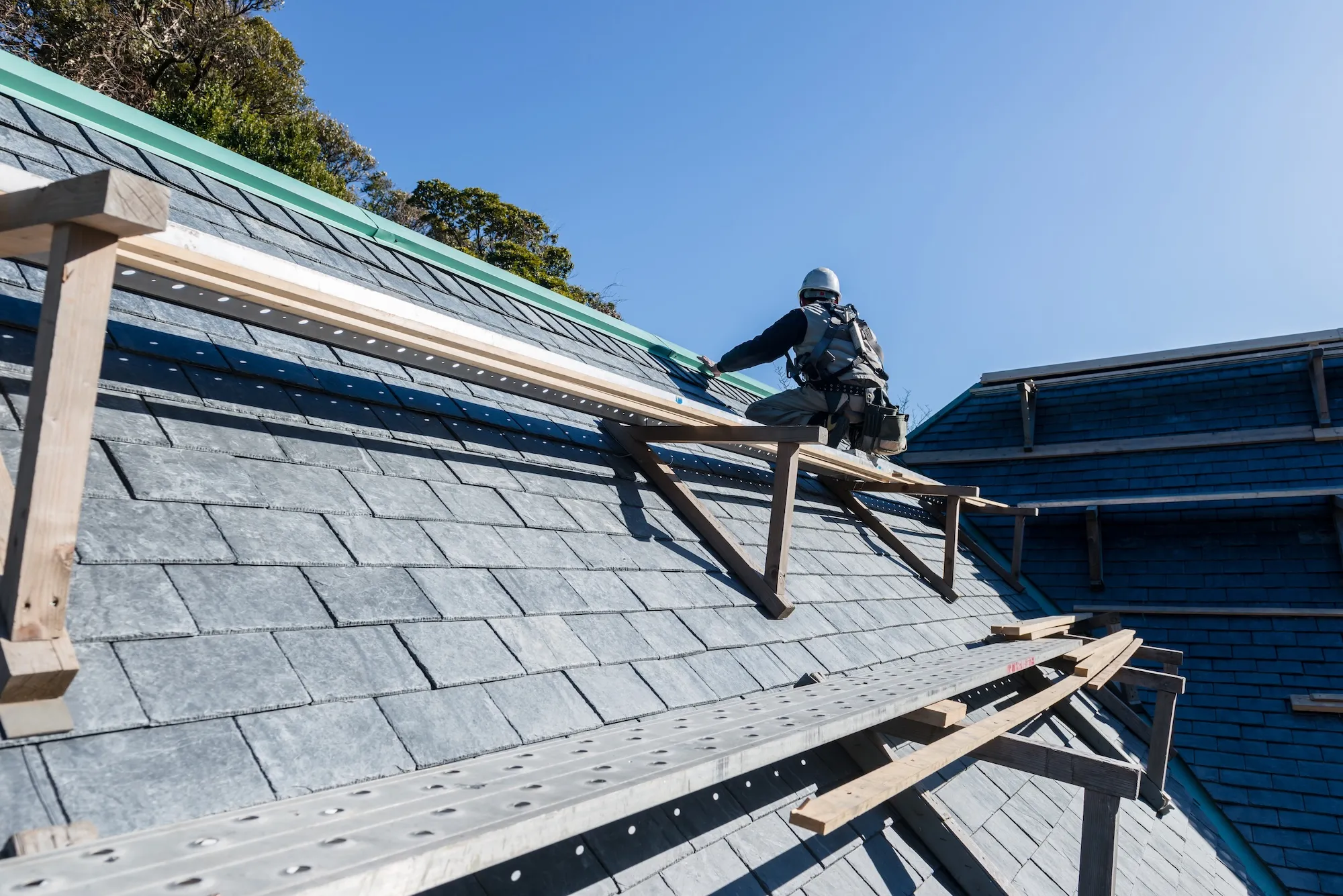 屋根に足場を組んで作業する職人