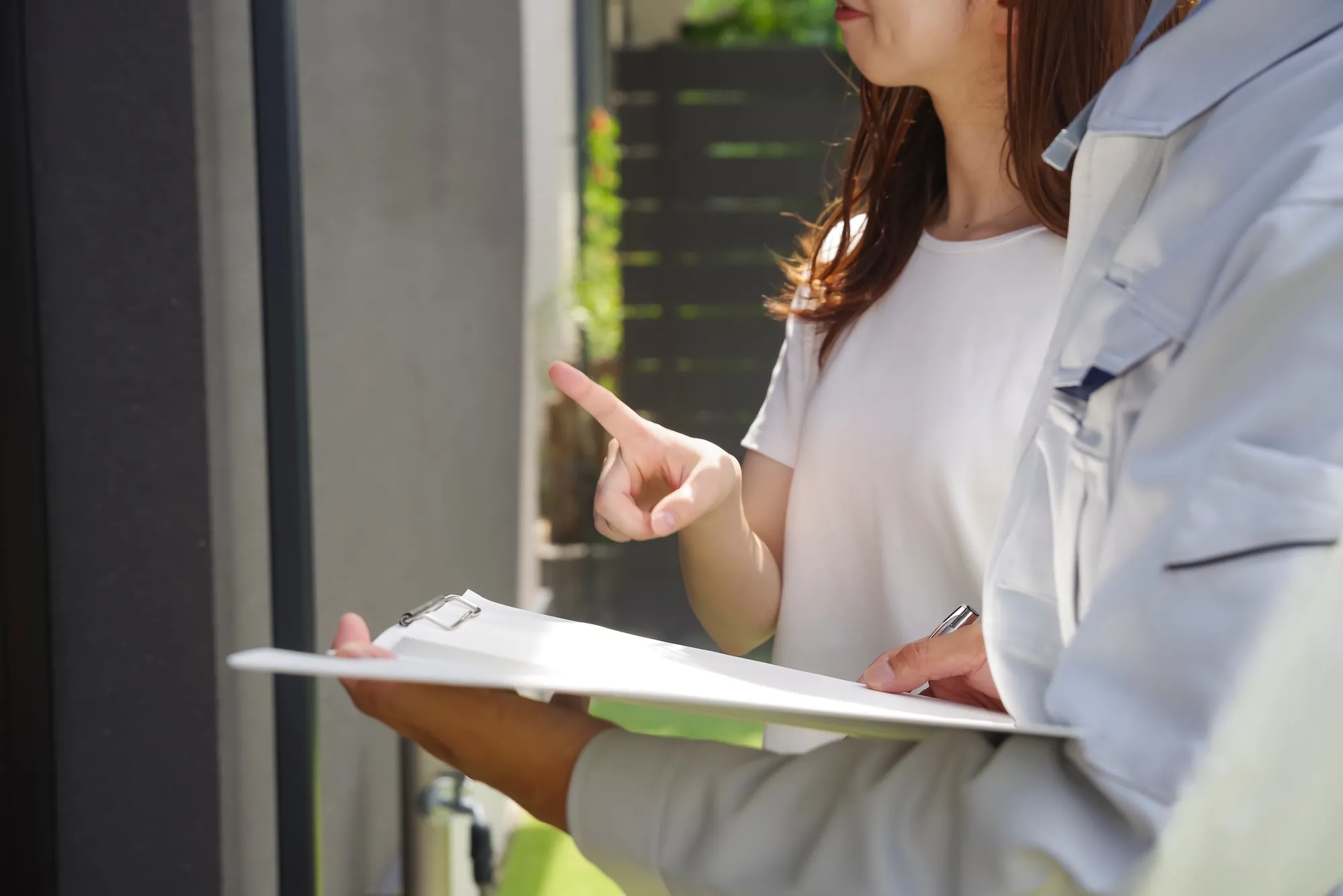 現地で女性の話を聞きながら、条件を整理するリフォーム会社担当者