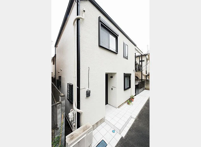 アイボリーの外壁と黒の設備のコントラストがおしゃれなリノベーション後の住宅外観