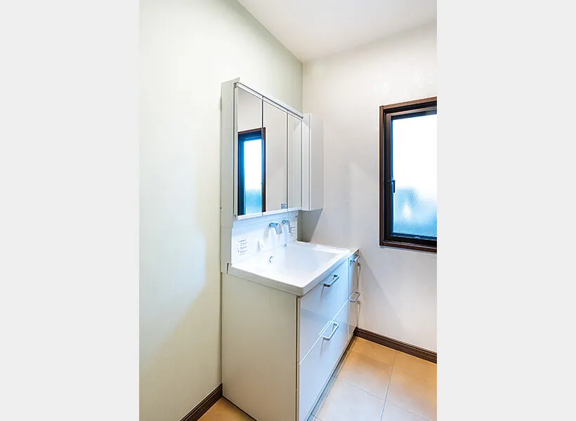 薄いグリーンのアクセントクロスと白い洗面化粧台