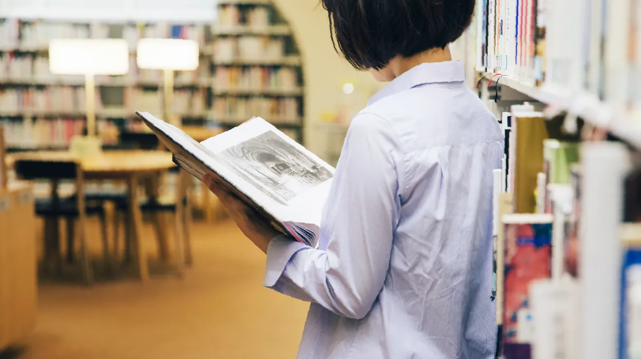 ひと・まち・情報 創造館 武蔵野プレイス館内で椅子に座り、本を読む利用者の様子