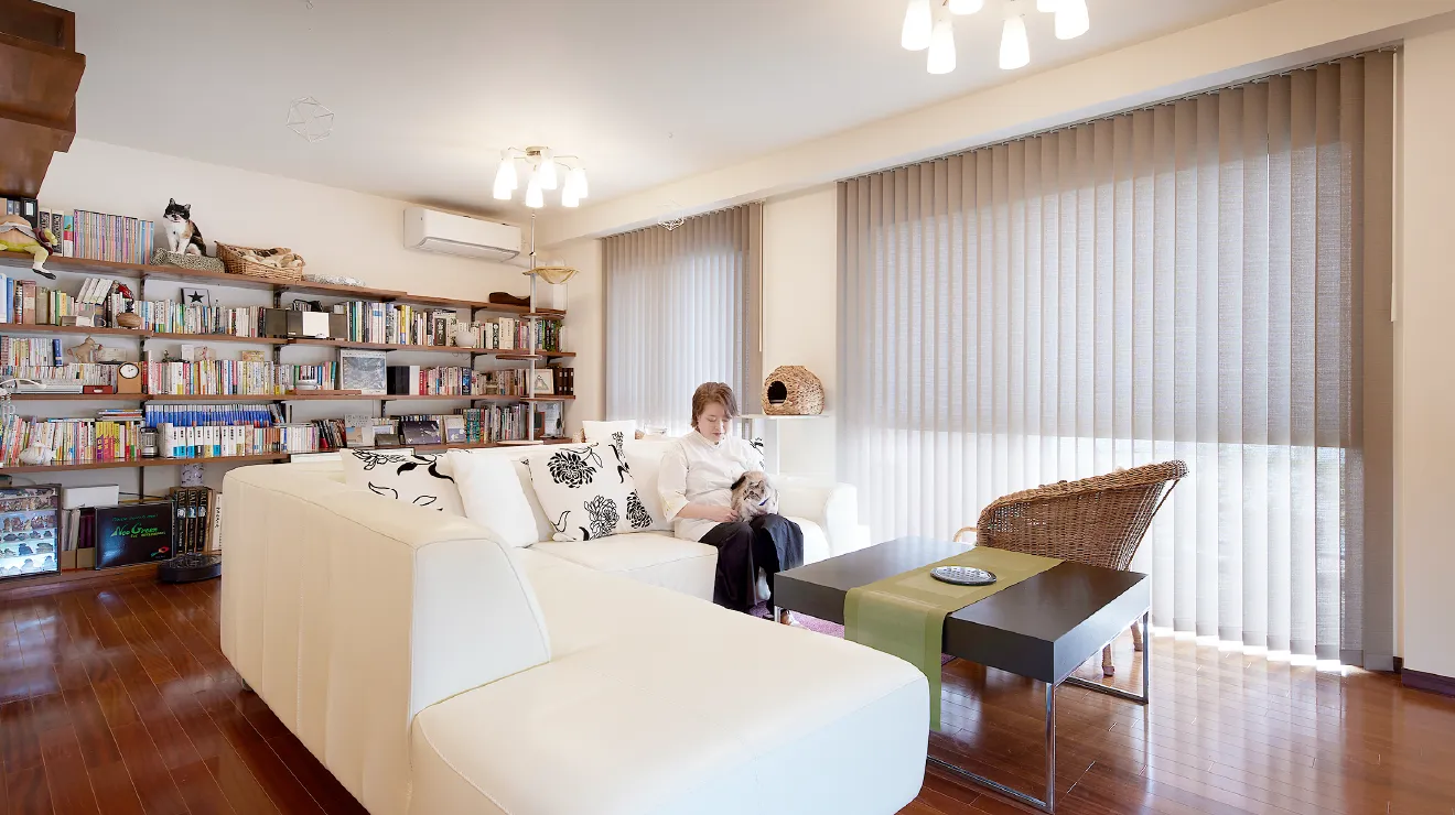白いソファのあるリビングで、膝に猫を抱く一級建築士・金巻とも子さん