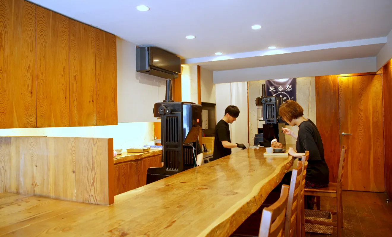 『天然氷かき氷けい』 の店内。左奥に立つ三浦さんと、カウンターでかき氷を楽しむお客さんの様子