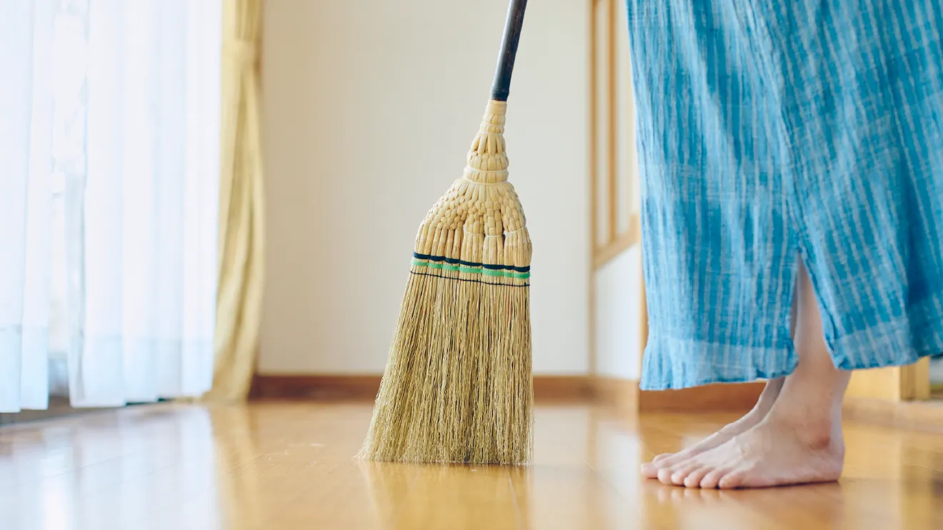 木の床を江戸箒で掃く素足の人の足元
